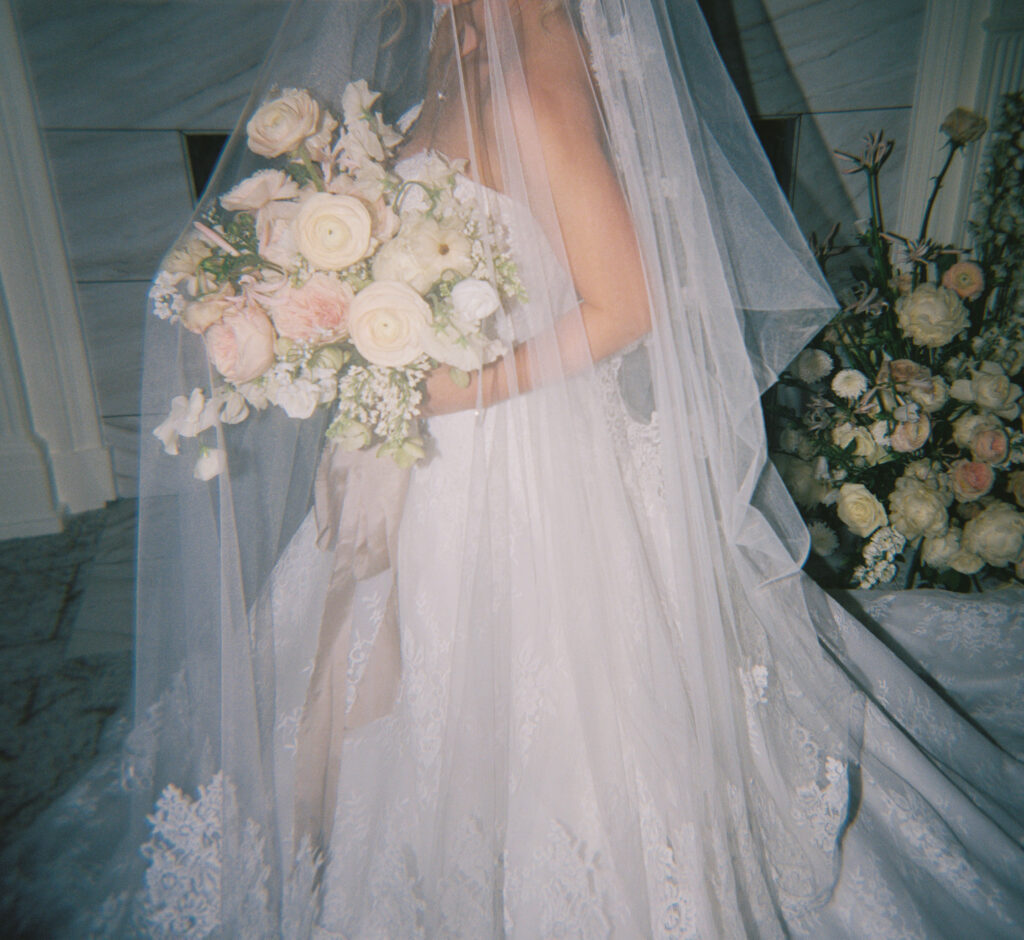 Film photograph of a bride adorned with her veil from The Bridal Bar, in front of a fireplace. 