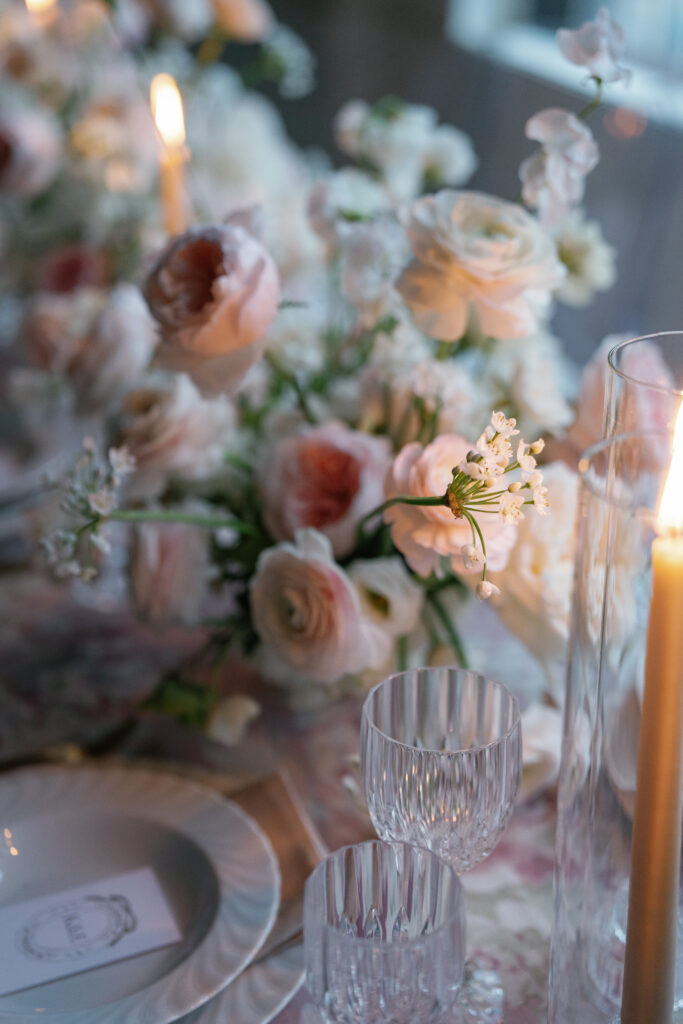 Ambient candle close-up on the head table at a wedding reception. David Austin garden roses and a pink color palette. 