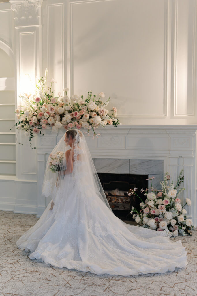 A bride in front of a grand fireplace, with large-scale flower installations