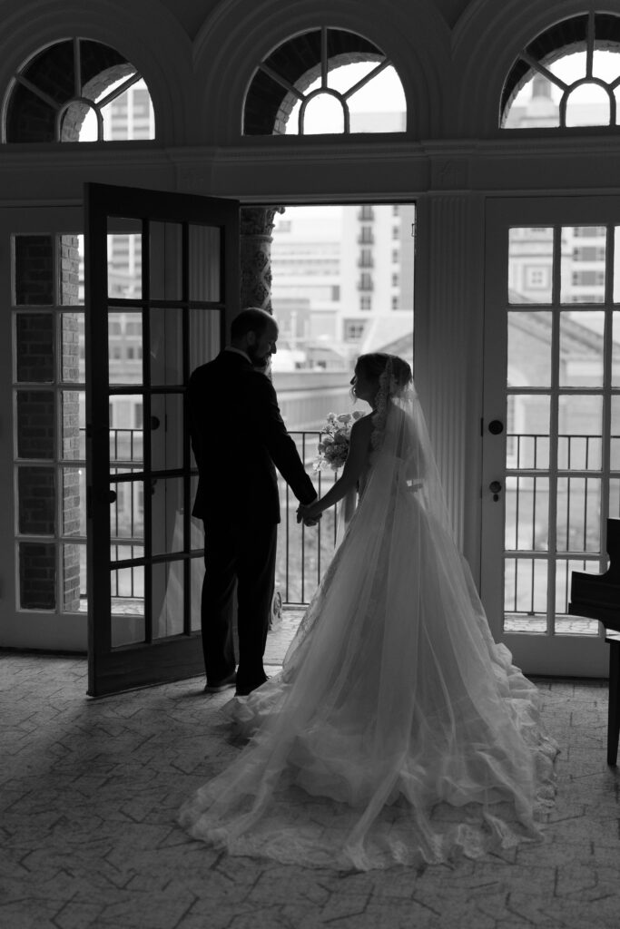 Black and white photo of a bride and groom in the doorway, overlooking the cityscape of downtown Fort Wayne, Indiana. 