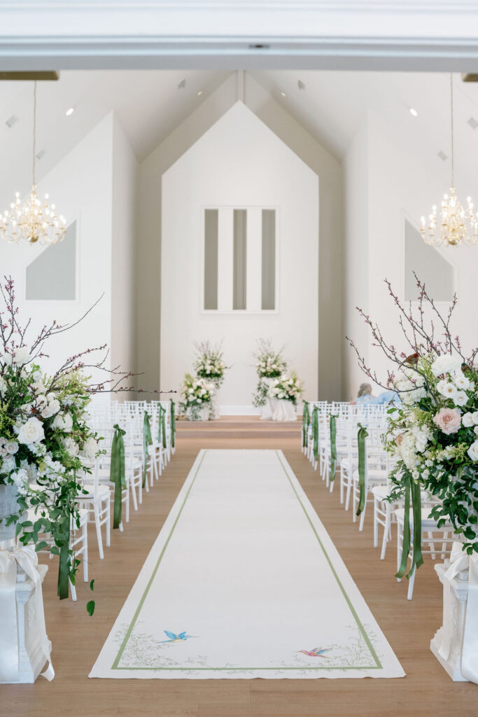 Wide shot of Ritz Charles Chapel with garden-style flowers and a hand-painted aisle runner
